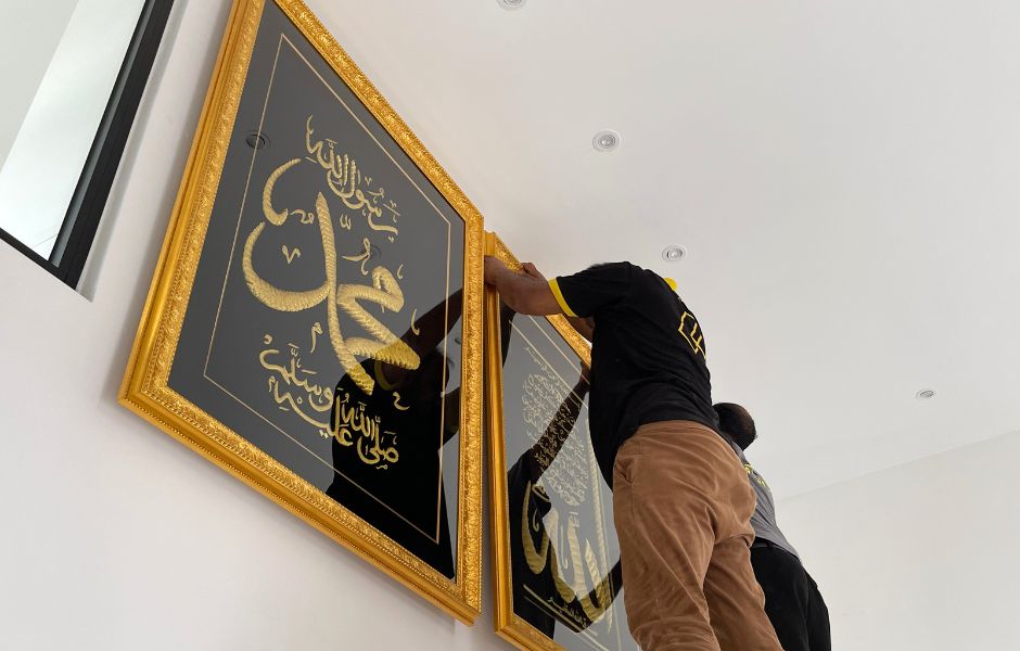 Frame Sifu technician installing a gold-framed Islamic calligraphy artwork