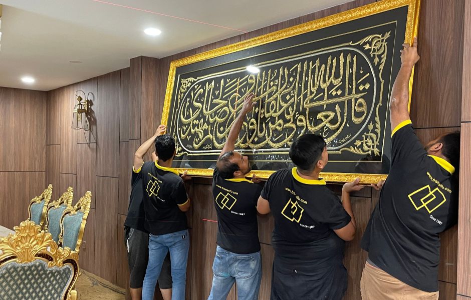 Frame Sifu team installing a large wooden Arabic calligraphy panel