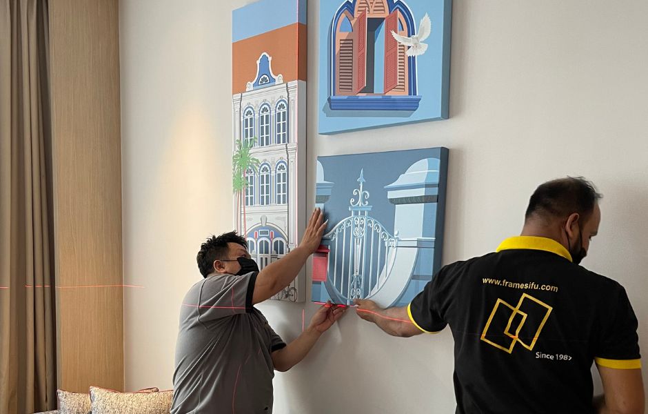 Frame Sifu technician hanging colourful framed prints in a residential bedroom